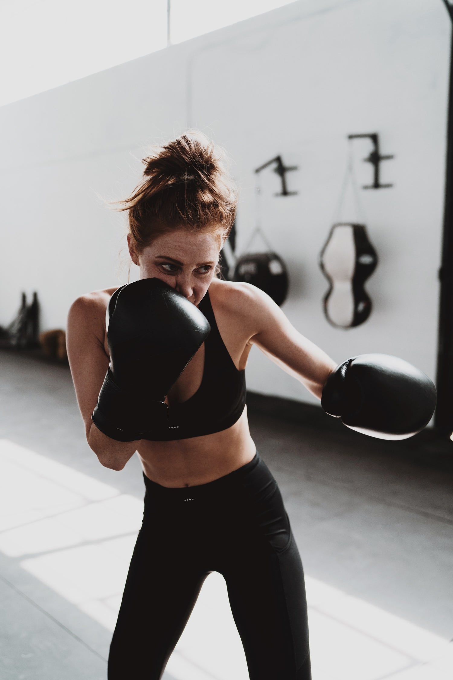 Neue Supply Co. woman boxing in all-black sports bra and leggings