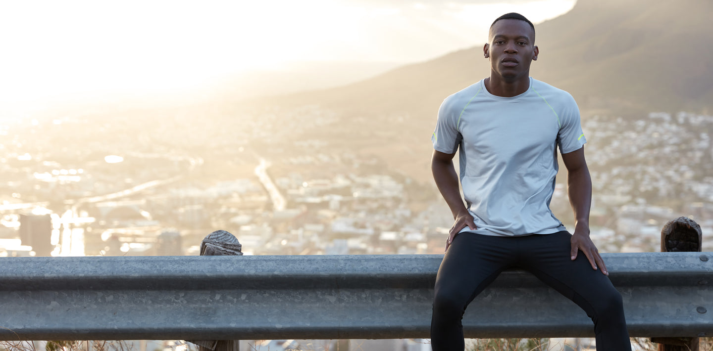 Man wearing all athleticwear sits on road overlooking city