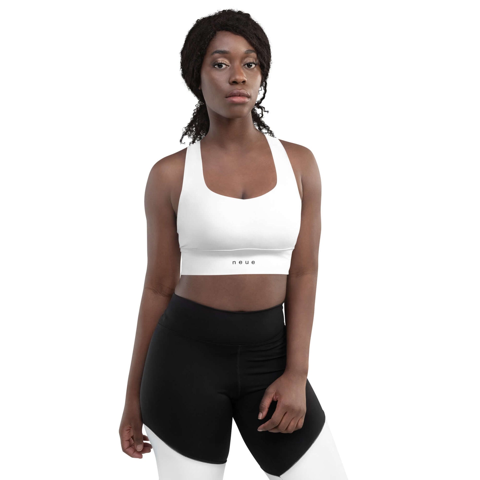 Woman wears Neue Supply Co. Longline Sports Bra in White. Front view of model looking into camera with white background.