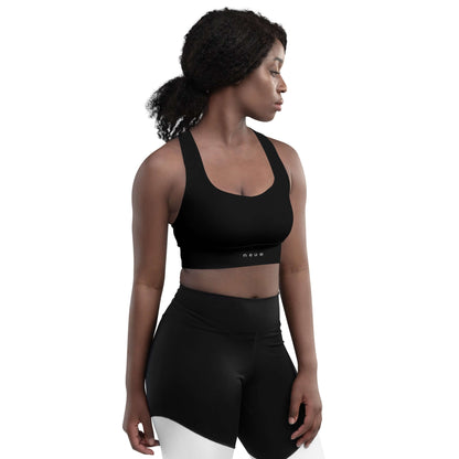 Woman wears Neue Supply Co. Longline Sports Bra in Black. Front view of model with white background.
